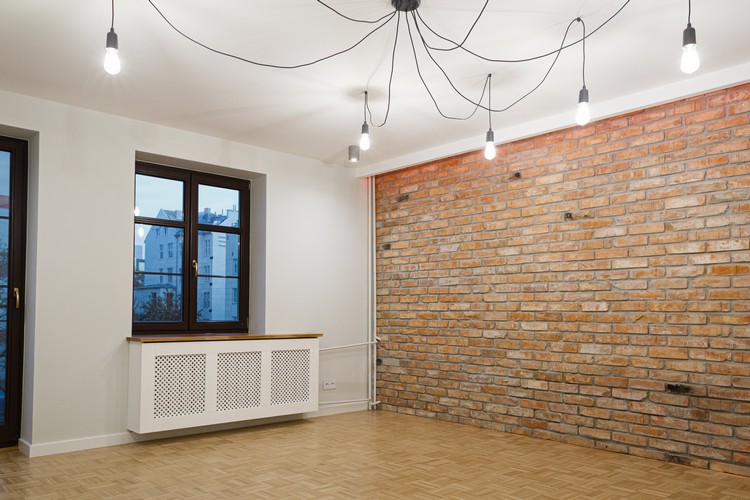 Wnętrze salonu w stanie surowym ze ścianą z surowej cegły